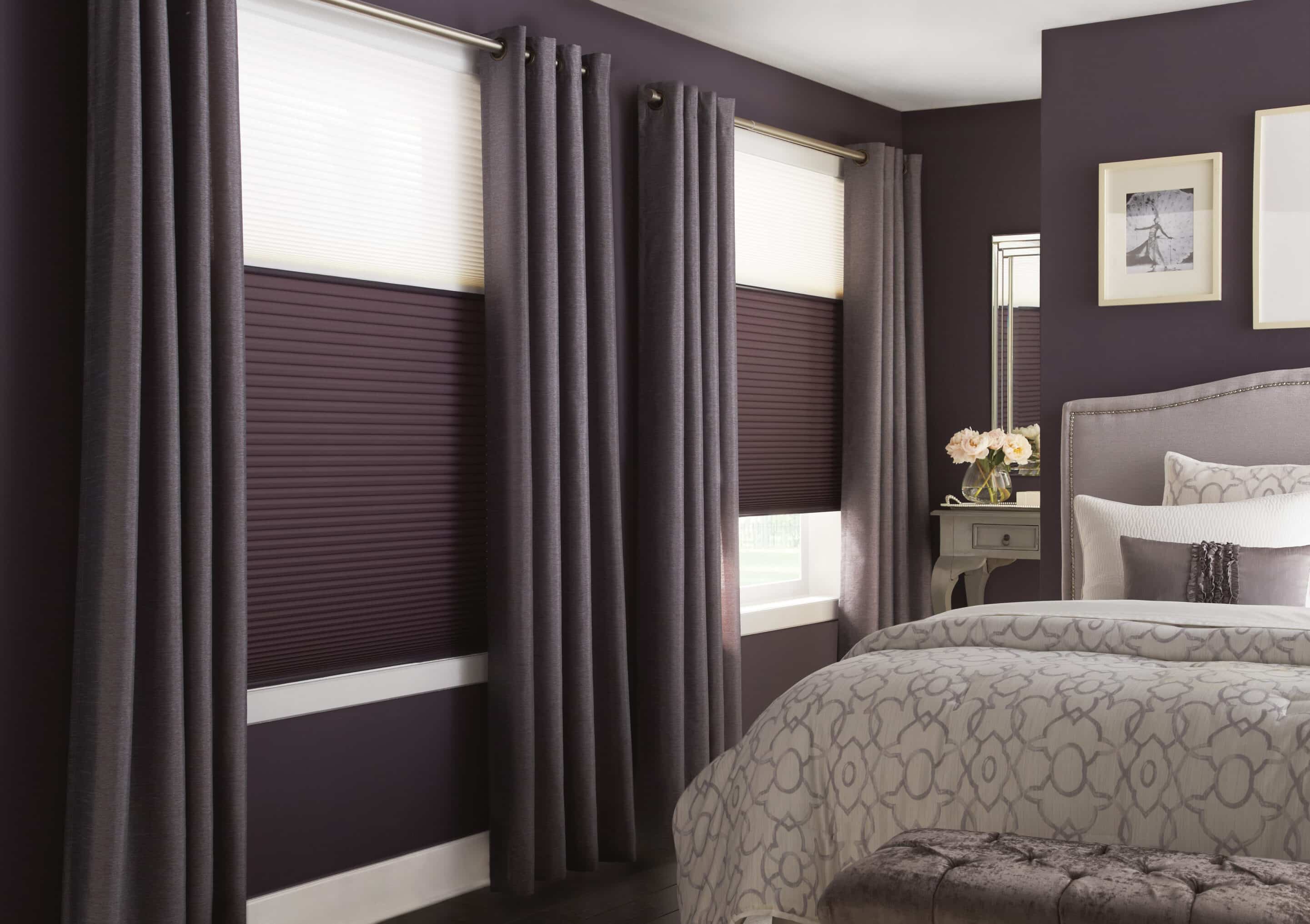 Bedroom with purple walls, layered curtains and cellular shades on windows.