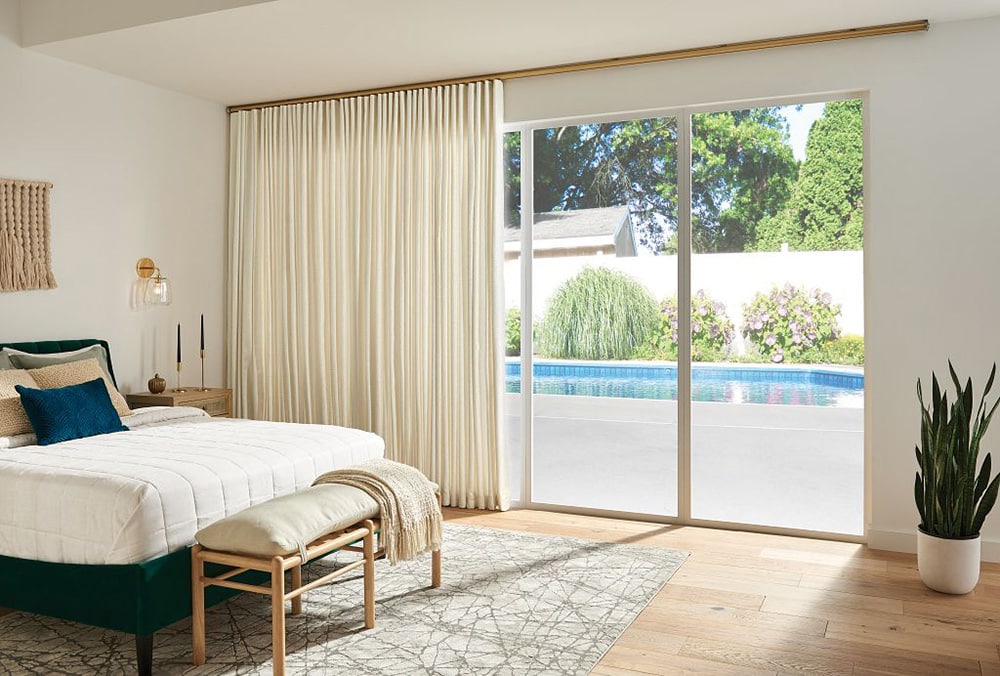 Custom drapery in a master bedroom looking out over a backyard pool.
