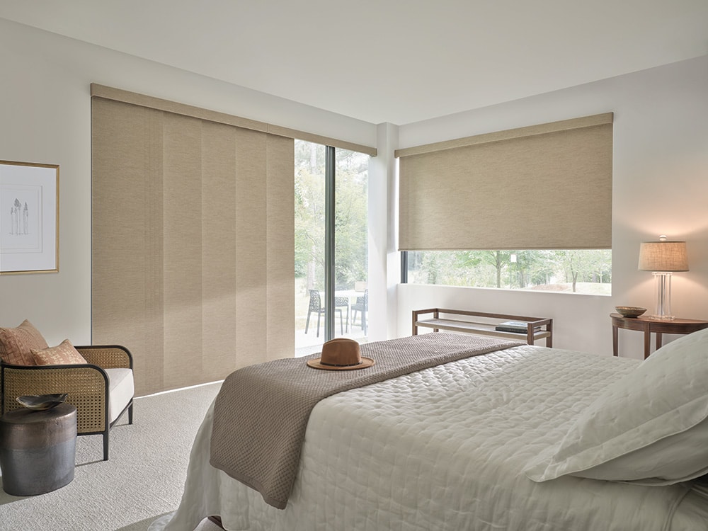 Roller shades both on a sliding glass door and a large window filtering in light into a master bedroom.